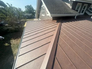 Standing seam metal roof with brown finish panels and professional seaming on residential home
