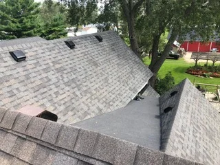 Gray asphalt shingle roof with new flashing and gutters on residential home