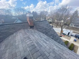 New asphalt shingle roof with brick chimney and proper flashing installation