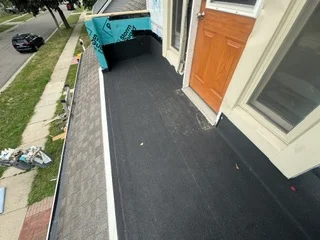 Dark membrane flat roof installation on residential home with clean edges and complete coverage