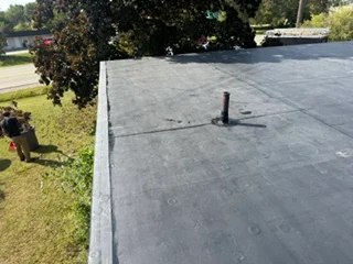 Dark membrane flat roof with sealed seams and roof penetration flashing