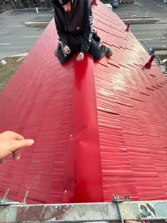 Red metal roof panels with standing seam installation and proper alignment