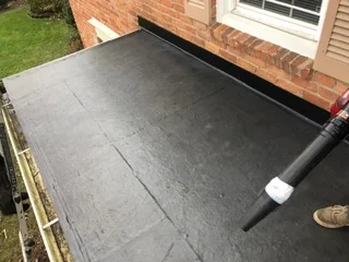 Black membrane flat roof with integrated drainage gutter and downspout installation