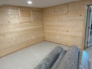 Wood-paneled interior room with pine tongue-and-groove walls and electrical outlets