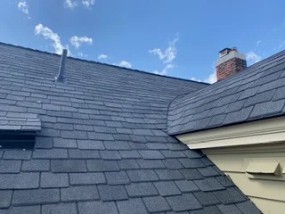 Slate gray architectural shingles with valley flashing and brick chimney on pitched roof