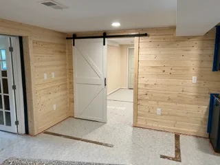Pine stud framing with drywall, barn door, and recessed lighting in interior space