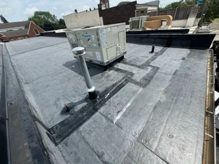 Commercial flat roof with membrane system, HVAC units, and metal flashing