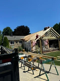 Residential roof framing with new trusses, decking, and construction equipment on-site