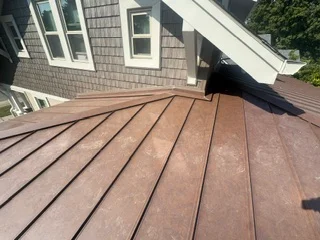 Standing seam metal roof with warm brown panels and linear striping pattern