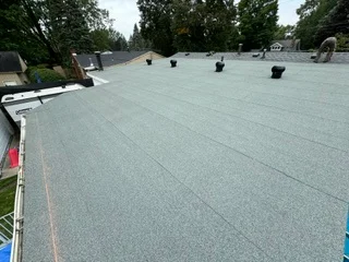 Flat roof with gray membrane material and multiple black roof vents installed