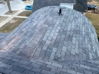 Gray asphalt shingle roof installation on pitched residential roof with multiple slopes