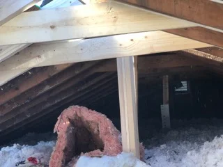 Attic framing with new wooden beams and joists installed in structural repair work