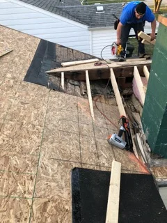 Roofer installing asphalt shingles on residential roof with wooden staging
