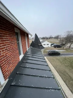 Newly installed asphalt shingle roof on brick home with ridge cap and flashing