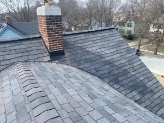 Newly installed asphalt shingle roof with brick chimney and proper flashing