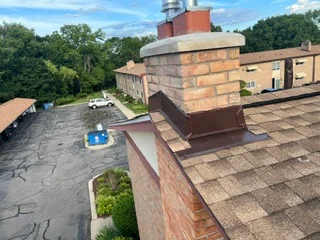 New asphalt shingle roof with brick chimney and metal flashing installation