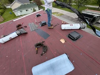 Roof repair in progress with removed shingles and new materials staged for installation