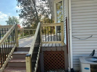 Two-level composite deck with brown boards, black metal railings, and built-in storage bench