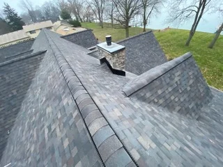Gray dimensional asphalt shingles installed on multi-plane roof with flashing and underlayment visible