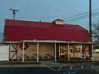 Red standing-seam metal roof on commercial building with open-air covered structure below