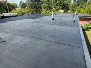 Dark membrane flat roof with drainage system and perimeter edge detail