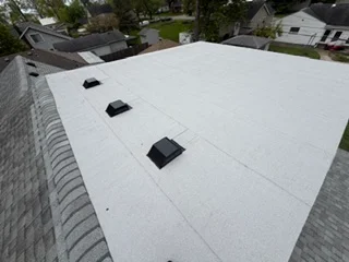 White membrane flat roof with three black roof vents installed on residential home