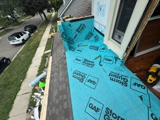 Blue roofing underlayment installed on residential roof deck with labeled synthetic felt