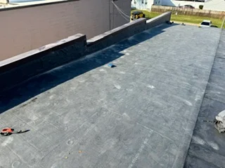 Flat roof with dark membrane material and perimeter flashing installation