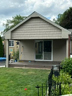 Residential home with new asphalt shingle roof and gray vinyl siding, gable vent detail visible