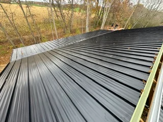 Standing seam metal roof installation with charcoal gray panels and clean seams